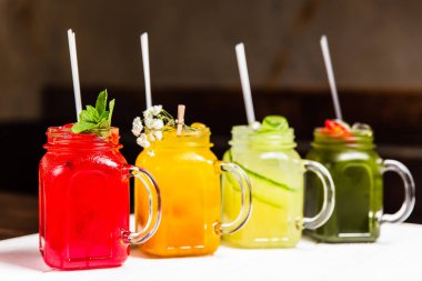 Kavanozlarda 4 farklı ferahlatıcı yaz limonatası, kırmızı, turuncu, sarı ve yeşil