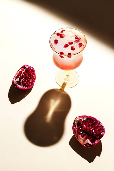 A beautiful glass of iced tonic water with pomegranate, hard back light, deep shadows