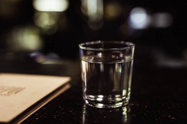 Karanlık ve kasvetli bir bar atmosferinde bir bardak su, seçici odaklanma.