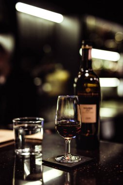 Belarus, Minsk, 26-06-2020: Bir bardak ve bir şişe şeri, karanlık ve kasvetli bir bar atmosferinde bir bardak su, seçici odaklanma