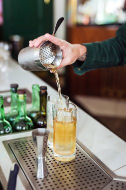 Barmen barda kokteyl hazırlıyor: bardaktan bardağa içki doldurmak.