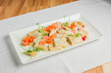 Krema soslu Paccheri makarna ve beyaz tabakta somon.