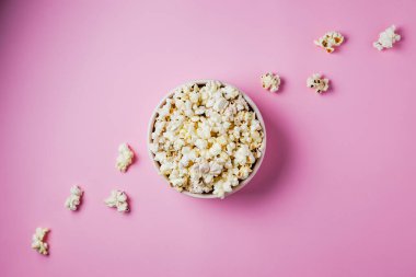 Pembe arka planda pembe bir kase patlamış mısır.