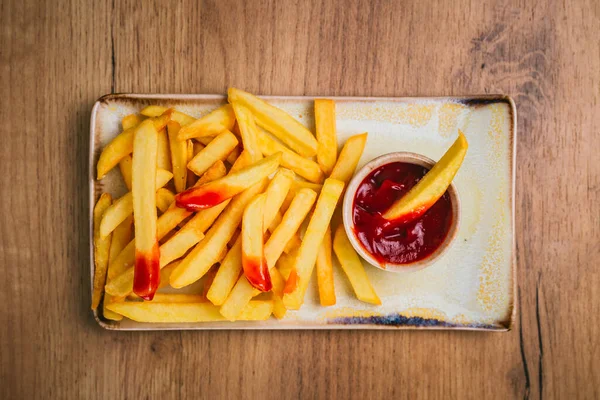 French fries with ketchup on a plate, top view