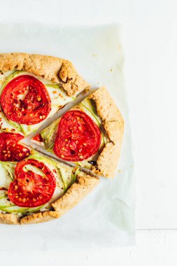 Ricotta peyniri, kabak ve domatesli bir galet, beyaz kabartma kağıdı, beyaz arka plan, üst manzara.