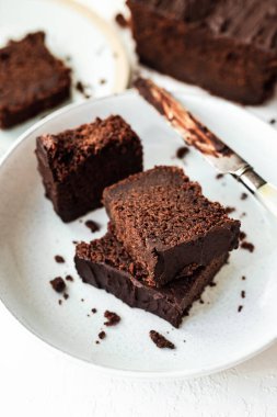 İki tabakta servis edilen dilimlenmiş çikolatalı kek, çikolata kaplı bir bıçak, yüksek anahtar, beyaz arka plan