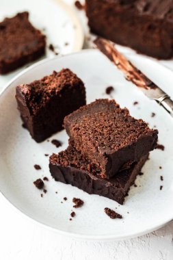 İki tabakta servis edilen dilimlenmiş çikolatalı kek, çikolata kaplı bir bıçak, yüksek anahtar, beyaz arka plan