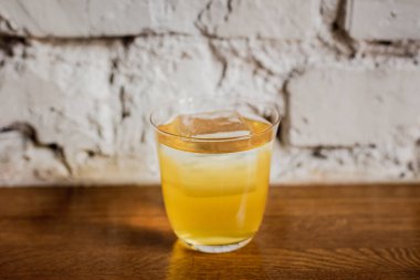 Parlak sarı bir kokteyl, buzlu, buzlu, sade bardakta.