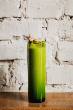 Fıstıkla süslenmiş yeşil bir viski bardağında uzun bir kokteyl.