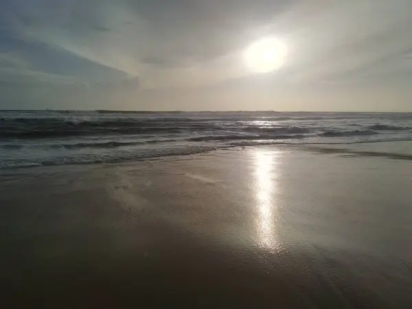 Fotoğraf plajda çekildi. Güneş ışınları altın kumu yansıtıyordu. 