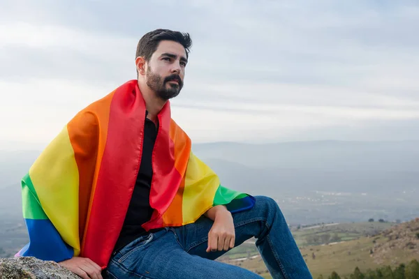 Gay bayraklı bir adam ufka bakıyor. Gey, gurur, çeşitlilik kavramı.
