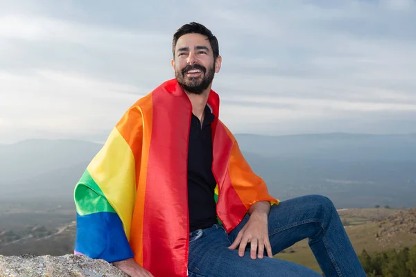 Eşcinsel gülüşü, gökyüzü arka planındaki ufukta gay bayrağıyla oturuyor. Eşcinsel, gurur, çeşitlilik kavramı