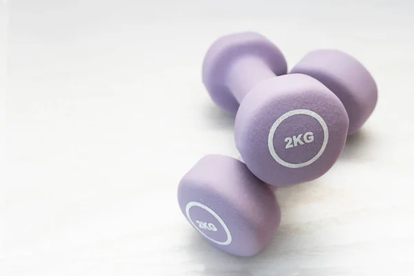 İki kiloluk mor halterler arka planda üst üste yığılmış. fitness konsepti