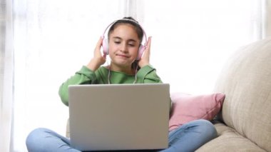 Kulaklıklı kız bacaklarındaki dizüstü bilgisayarın ritmini takip ediyor.