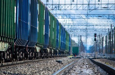 Demiryolu trafik ışıkları, otoparktaki mavi ve yeşil arabalar, mesafeye giden demiryolu rayları, tren yolu üzerindeki kablolar.