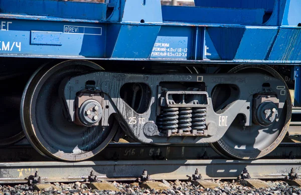 A freight train with blue and green wagons is parked at the railway station. Wagon wheels close-up