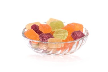 Beyaz arka planda cam tabakta duran renkli marmelat şekerleri.