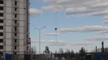 İnşaat alanı. Çok katlı bir bina inşa ediliyor. İnşaat vincinden kancalı yük bekliyor.