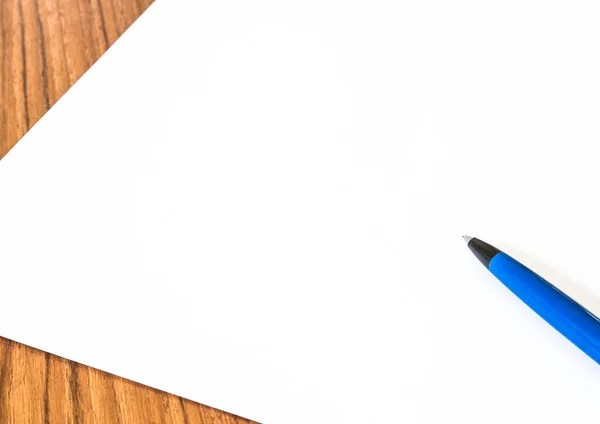 木製のテーブルの上に白い紙と青いペンのレイアウトのショット — ストック写真