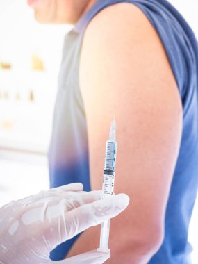 Beyaz lastik eldiven takan eller. Şırıngayı tut. İçinde ilaçlar, aşılar var. Olay yerindeki adamın kollarına yapılan iğne.