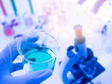 Cam bir deney tüpü tutan bir bilim adamının elinde sıvı, bilim masası olarak arka plan, kimyasal yapı grafikleri, renk tonları vardır. yakın plan