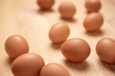 Açık kahverengi ahşap arka planda çiğ tavuk yumurtalarını kapatın.