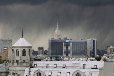 Şehir manzarası, binalar, anıtlar, çatılar, karanlık fırtınalı bir gökyüzünde çatılar ve kara yağmur bulutları. Moskova, Rusya
