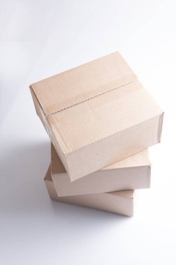 Üç kapalı dikdörtgen boş kahverengi karton kutunun kapalı yakın çekim görüntüsü beyaz arka planda.