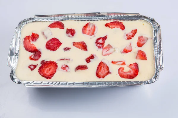Bir Rus zapekanka çilekli puding kulübesinde beyaz bir arka planda folyo pişirme tavasında dondurmalı kek.