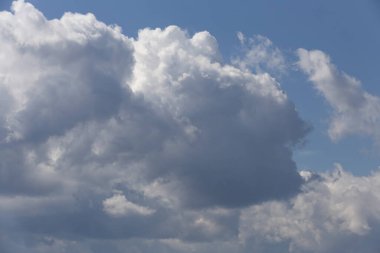 Güzel pofuduk pamuk şeker, beyaz bulutlar, mavi gökyüzü arka planında koyu gölgeler.
