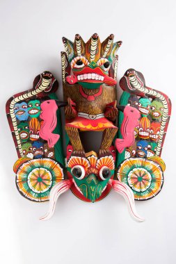 vertical isolated close up shot of a traditional Sinhalese (Sri Lanka) carved wooden Raksha mask of the Maha Kola demon with eighteen smaller demons on a white background clipart