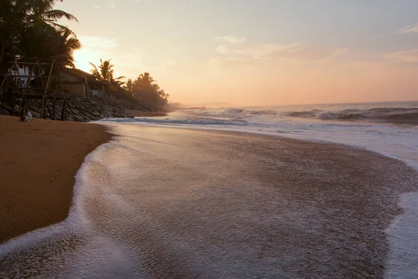 在日出时分 美丽的明信片拍下了皮特韦拉海滩 斯里兰卡 的风景 这里有橙色的沙子 绿色的棕榈树 褐色的岩石 白浪汹涌的印度洋和地平线上的太阳 — 图库照片