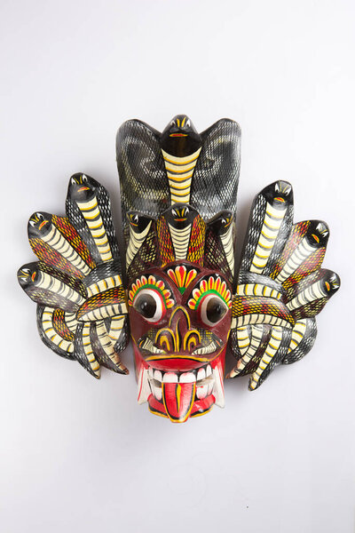 vertical isolated close up shot of a traditional Sinhalese (Sri Lanka) carved wooden black Raksha mask of the Dwi Naga twin cobra devil on a white background