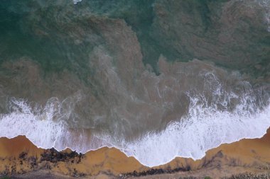 Sarı kum, siyah kayalar, büyük beyaz dalgalar ve köpüklerin sahile çarptığı deniz manzaralı hava aracı görüntüsü güzel dokular, desenler, şekiller oluşturuyor. Sri Lanka