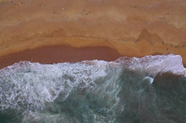 Turkuaz mavi su, büyük beyaz dalgalar ve köpük, sarı kumlu boş plaj, siyah kayalar, güzel dokular, desenler ve şekiller oluşturan deniz uçağı görüntüsü. Sri Lanka