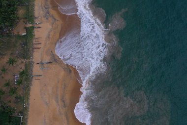 Hava aracının turkuaz suyla deniz kıyısı görüntüsü, uzun balıkçı tekneleri, beyaz dalgalar ve köpüklerle dolu boş bir kumsal güzel dokular, desenler ve şekiller oluşturuyor. Sri Lanka