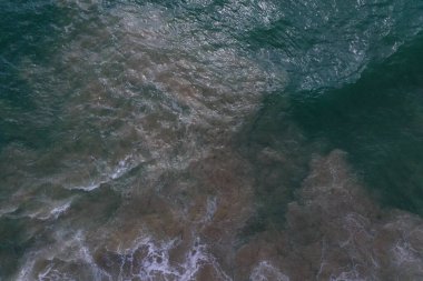 Deniz yüzeyinin turkuaz mavi su, büyük beyaz dalgalar, köpük ve sualtı kumları, güzel dokular, desenler ve şekiller oluşturan hava aracı görüntüsü. Sri Lanka