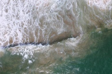 Deniz yüzeyinin turkuaz mavi su, büyük beyaz dalgalar, köpük ve sualtı kumları, güzel dokular, desenler ve şekiller oluşturan hava aracı görüntüsü. Sri Lanka