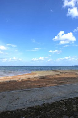 Gölgede boş sarı kumsal manzarası, turkuaz okyanus suyu, açık mavi gökyüzü, ufukta beyaz bulutlar ve adalar. Koh Lanta Adası, Tayland