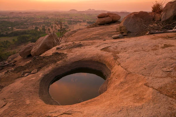 Hindistan, Hampi 'deki Hanuman Dağı' nın tepesinde içinde su olan bir krater oluştu. Fotoğraf, altın saat boyunca kırmızı bir günbatımında çekiliyor. Mars gibi görünüyor.