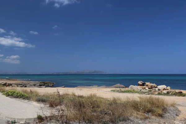西班牙美丽多姿多彩的马略卡岛上 绿草碧绿碧绿海水 蓝天白云映衬的荒凉岩石海滩全景 — 图库照片