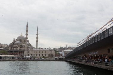 ISTANBUL / TURKEY - 30 / 05 / 2015: Bulutlu bir arkaplanda minareler bulunan balıkçılar, restoran terasları, barlar ve Yeni Cami (Yeni Cami) ile Galata Köprüsü 'nün gündüz manzarası.