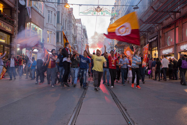 ISTANBUL / TURKEY - 30/05/2015: big crowd of Galatasaray S.K. football team fans marching with banners, flags, flares on Istiklal walking street, chanting, screaming, singing, celebrating a victory