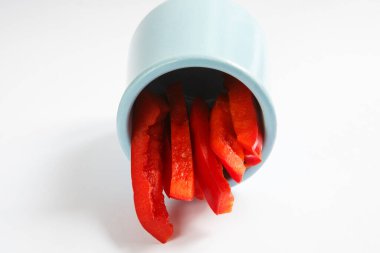 Ayrıntılı izole edilmiş fotokopi alanı beyaz arka planda mavi yuvarlak kil seramik kavanozda taze ıslak kırmızı dolma biber yığınının yemek çekimini kapat