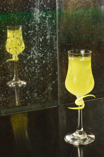 Arkadaki kirli aynaya yansıyan şeffaf bir bardakta şeffaf bir limoncello limonata kokteyli.