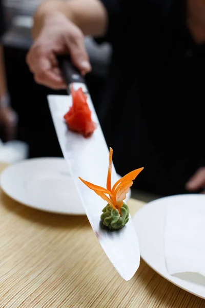 水壶的垂直镜头模糊了男性的手 男性的手拿着一把长长的菜刀放在桌子上方 菜刀上有一小堆红色刺青和日本青椒酱 — 图库照片