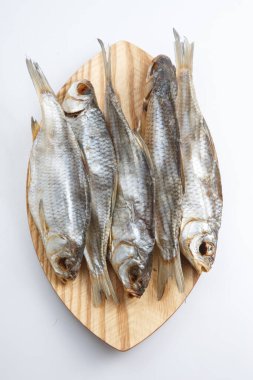 Beyaz bir zemin üzerinde ahşap bir tabakta kurutulmuş beş Rus voblasının (Kaspiyan hamamböceği) üst görüntüsünü kapat.