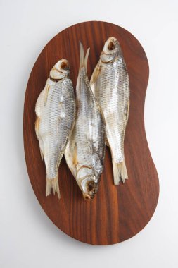 Beyaz arka planda, koyu ahşap bir tabakta üç Rus kurutulmuş voblasının (Hazar böceği) yakın çekim görüntüsünü izole ettim.