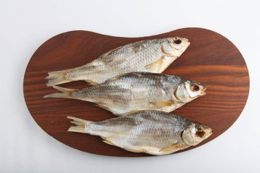 Beyaz arka planda, koyu ahşap bir tabakta üç Rus kurutulmuş voblasının (Hazar böceği) yakın çekim görüntüsünü izole ettim.