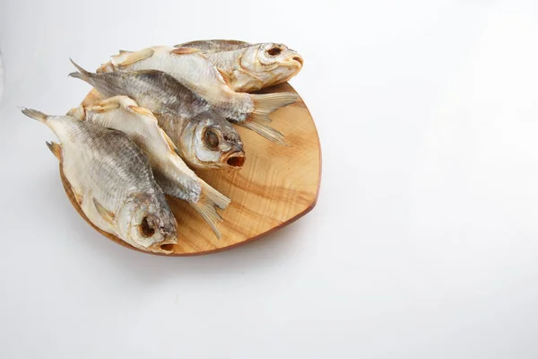 close up top corner shot of a bunch of five Russian dried salted vobla (Caspian Roach) fish on a wooden plate on a white background